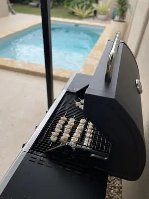 a grill with some food on it next to a pool at Casa Tres Luces - Samara Home in Nicoya