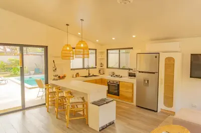 a kitchen with a refrigerator and a table with chairs at Casa Tres Luces - Samara Home in Nicoya
