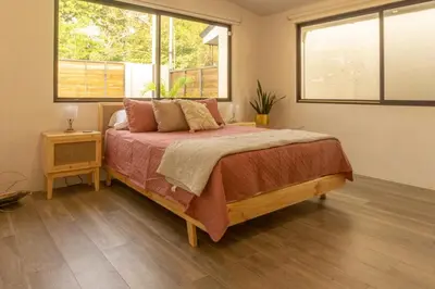 a bedroom with a bed and two windows at Casa Tres Luces - Samara Home in Nicoya
