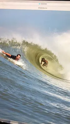 two people riding a wave on surfboards in the ocean at Hotel Clandestino beach resort in Parrita