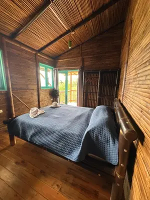 a bedroom with a bed in a wooden room at Eco-Bamboo Cottages in Turrialba