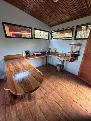 a room with a wooden table in a room with windows at Eco-Bamboo Cottages in Turrialba