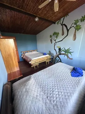 a bedroom with a bed and a tree on the wall at Eco-Bamboo Cottages in Turrialba