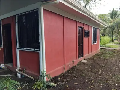 a red building with two doors and a window at Monkey Beach House in Tortuguero