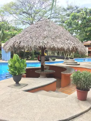 a large straw umbrella sitting next to a pool at CocoMarindo in Coco