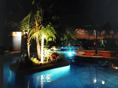 a pool at night with palm trees and lights at CocoMarindo in Coco