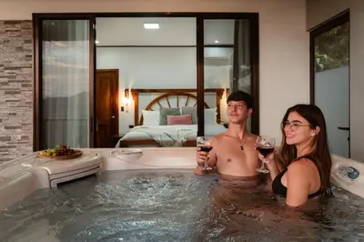 a man and a woman sitting in a bath tub with wine glasses at Villa Alma de Campo Monteverde in Monteverde Costa Rica
