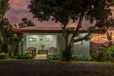 a house with two chairs in front of it at Villa Alma de Campo Monteverde in Monteverde Costa Rica