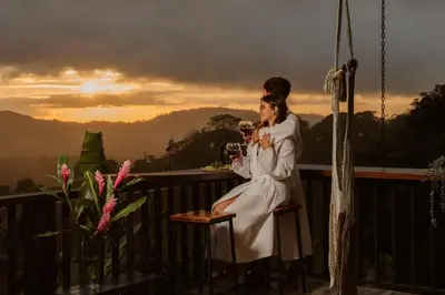 a bride and groom sitting on a balcony with wine glasses at Villa Alma de Campo Monteverde in Monteverde Costa Rica