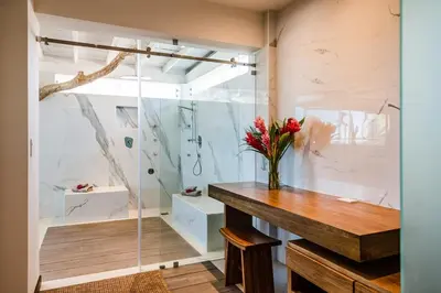 a bathroom with a vase of flowers on a wooden table at The Point 5-Star All-Inclusive Experience in Tamarindo
