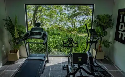 a gym with two tread machines and a large window at The Point 5-Star All-Inclusive Experience in Tamarindo