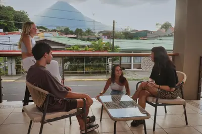 a group of people sitting in chairs on a porch at Ceiba Hostel in Fortuna