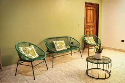 three green chairs and a table in a room at Ceiba Hostel in Fortuna