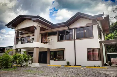 a white house with a lot of windows at Ceiba Hostel in Fortuna