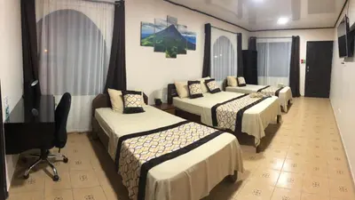 a hotel room with four beds and a desk at HOTEL DEL RiO in Liberia