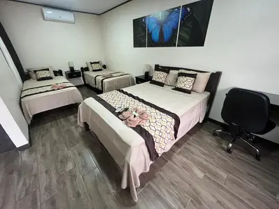 a bedroom with two beds and a desk and a chair at HOTEL DEL RiO in Liberia
