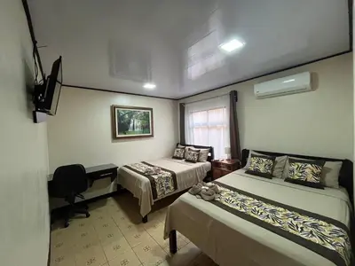 a room with two beds and a desk and a window at HOTEL DEL RiO in Liberia