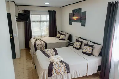 a hotel room with two beds and a mirror at HOTEL DEL RiO in Liberia