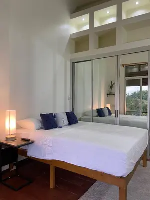 a large white bed in a room with a lamp at villa country club cariari in Ciudad Cariari