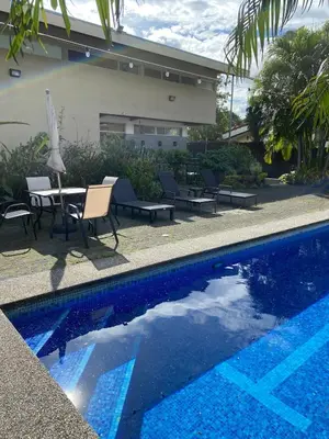 a swimming pool with chairs and a table and an umbrella at villa country club cariari in Ciudad Cariari