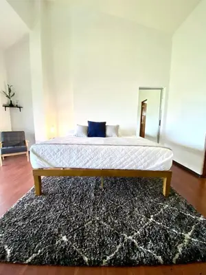 a bed in a bedroom with a rug on the floor at villa country club cariari in Ciudad Cariari