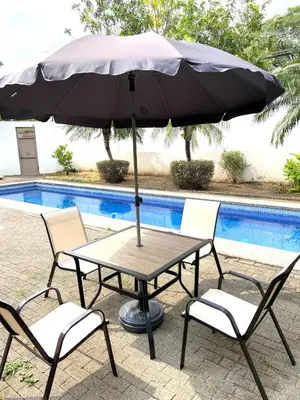 a table and chairs with an umbrella next to a pool at villa country club cariari in Ciudad Cariari