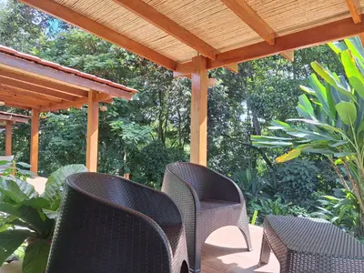 a patio with chairs and a wooden pergola at Olla é Mono Ecolodge in Sarapiquí