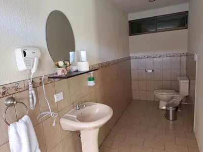 a bathroom with a sink and a toilet and a mirror at Olla é Mono Ecolodge in Sarapiquí