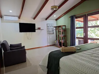 a bedroom with a bed and a chair and a television at Olla é Mono Ecolodge in Sarapiquí