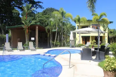 a pool with chairs and an umbrella next to a house at Club Del Cielo Unit 1 in Jacó
