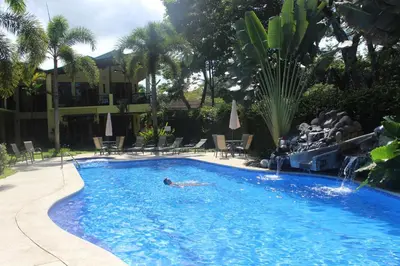 a person laying in a swimming pool in a resort at Club Del Cielo Unit 1 in Jacó