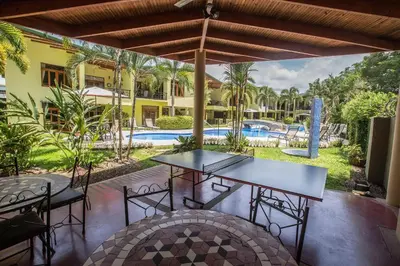 a patio with tables and chairs and a pool at Club Del Cielo Unit 1 in Jacó