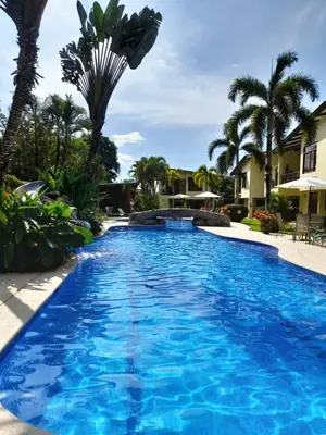 a swimming pool with blue water and palm trees at Club Del Cielo Unit 1 in Jacó