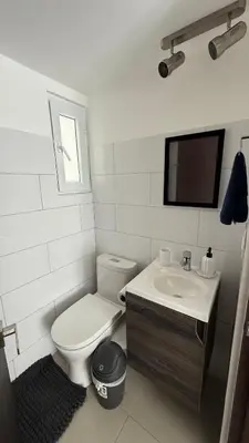 a white bathroom with a toilet and a sink at Khaya Curridabat in Curridabat