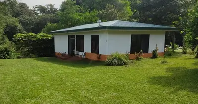 a small white house in a field of grass at Finca flo in Carara