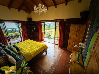 a bedroom with a bed and a chandelier at Hotel Poas Paradise in Alajuela City