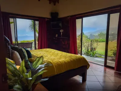 a bedroom with a yellow bed with a view of a field at Hotel Poas Paradise in Alajuela City