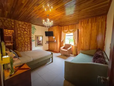 a bedroom with two beds and a chair and a chandelier at Hotel Poas Paradise in Alajuela City