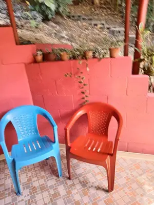 two plastic chairs sitting next to a red wall at Bowen apartamento in Quepos