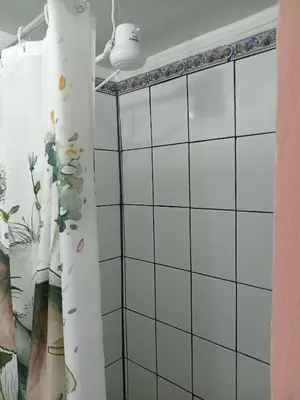 a bathroom with white tiled walls and a shower curtain at Bowen apartamento in Quepos