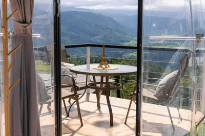 a balcony with a table and a view of the mountains at Glamping Renacer Vistas Turrialba, Paris in Turrialba