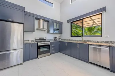 a kitchen with blue cabinets and a large window at CASA SERENITY , brand new house, walk 2 beach, private pool, wifi, PURA VIDA!!!! in Uvita