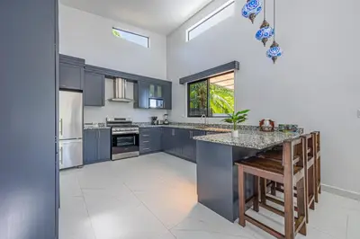 a kitchen with blue cabinets and a counter top at CASA SERENITY , brand new house, walk 2 beach, private pool, wifi, PURA VIDA!!!! in Uvita