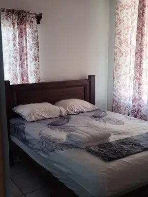 an unmade bed in a bedroom with two windows at Casa a solo 20 minutos aproximadamente de Manuel Antonio Beach y a 10 minutos aproximadamente del centro de Quepos in Quepos
