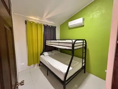 a room with two bunk beds and a green wall at Cabañas Corozalito in Corozalito