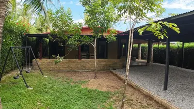 a house with a porch with two trees in the yard at Las Palmeritas de Ojochal in Tortugal