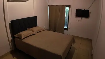 a bedroom with a bed and a television and a window at Las Palmeritas de Ojochal in Tortugal