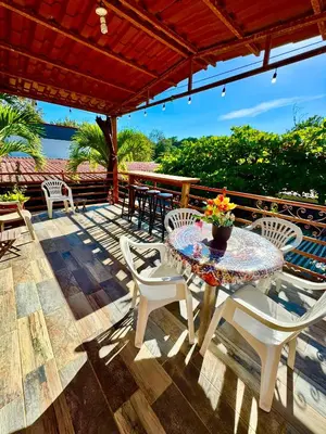a patio with a table and chairs on a deck at Villas Ela en Bahía Ballena Uvita hermosas habitaciones privadas grandes, piscina, cocina, jacuzzi, aire acondicionado, tv, baño privado, parqueo gratis y terraza in Uvita