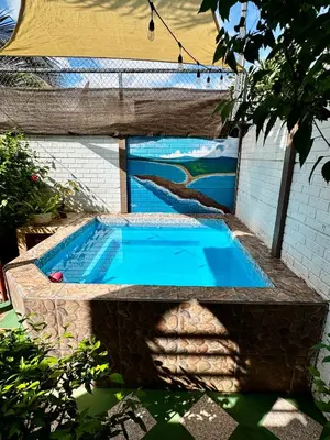 a swimming pool with a stone wall and a blue pool at Villas Ela en Bahía Ballena Uvita hermosas habitaciones privadas grandes, piscina, cocina, jacuzzi, aire acondicionado, tv, baño privado, parqueo gratis y terraza in Uvita