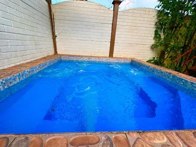 a large blue pool with a brick wall at Villas Ela en Bahía Ballena Uvita hermosas habitaciones privadas grandes, piscina, cocina, jacuzzi, aire acondicionado, tv, baño privado, parqueo gratis y terraza in Uvita